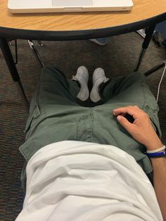 a man laying on the ground under a table with a laptop