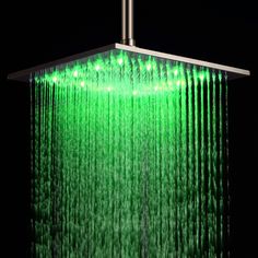 a green shower head with water running down it's side and the light is on