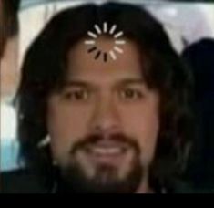 a man with long hair and a fake sunflower on his forehead is smiling at the camera