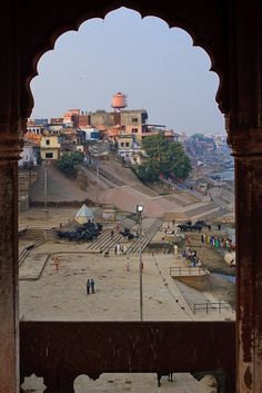 people are walking around in an open area with many buildings on the hill behind them