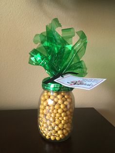 a glass jar filled with yellow and green candies on top of a wooden table