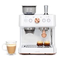 an espresso machine with two cups next to it on a white surface,