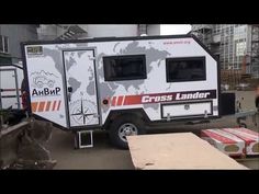 a small camper trailer is parked in the middle of an industrial area with other vehicles