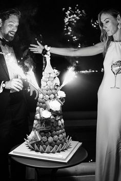 a man and woman holding sparklers near a cake