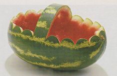 a watermelon bowl with two slices cut out and sitting on a white surface