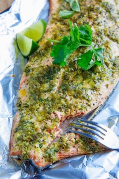 a piece of salmon covered in pesto and parsley with a fork on it