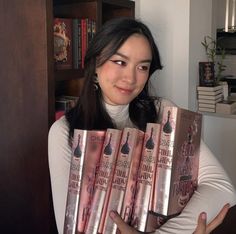 a woman holding five books in her hands