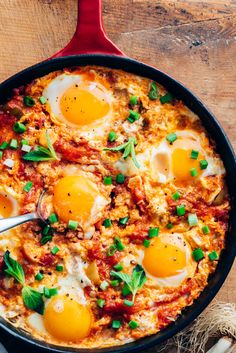 an iron skillet with eggs and spinach in it next to bread on the side