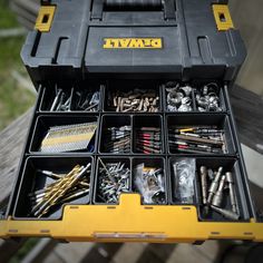 a tool box filled with lots of screws and other assorted tools sitting on top of a wooden table