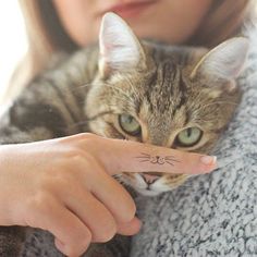 a woman holding a cat with a finger tattoo on it