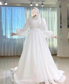 a woman in a white wedding dress with her hands out to the side, wearing a veil