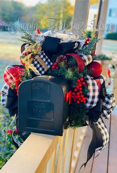 a christmas wreath is hanging on the side of a wooden fence with a mailbox