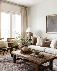 a living room filled with lots of furniture and pillows on top of a table in front of a window