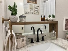 a white sink sitting under a bathroom mirror next to a wooden shelf filled with bottles