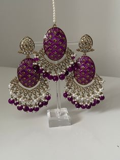 Please visit our website www.sakavano Jewellery.com for all offers.  A beautiful handpainted Kundan pair of earrings and tikka set that come with pearls.   These earrings are super lightweight and are a true statement piece.   Please follow out Instagram page @sakavano_jewellery for all our latest offers.  Please note we do not offer any refunds or exchanges due to hygiene reasons Purple Meenakari Sets For Diwali, Purple Kundan Jewelry Gift, Meenakari Jewelry Sets For Eid, Traditional Meenakari Purple Jewelry, Traditional Purple Jewelry For Festive Occasions, Purple Meenakari Wedding Sets, Elegant Purple Meenakari Jewelry, Traditional Purple Festive Jewelry, Festive Purple Chandbali Jewelry