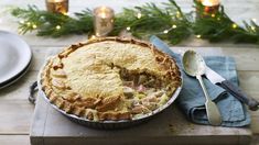 a pie sitting on top of a wooden table next to plates and utensils