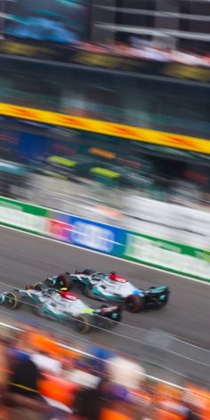 two race cars racing on a track in front of an audience