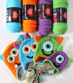 crochet monster hats and yarns are on the table with balls of yarn