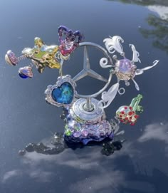 a car hood ornament with many different colored glass items on it's surface