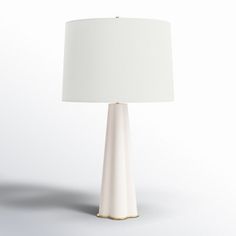 a table lamp with a white shade on the base and a gold trim around it