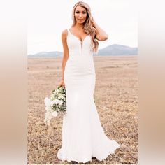 a woman in a white wedding dress holding a bouquet and posing for the camera with her hand on her head