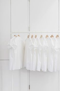 several white shirts hanging on a clothes rack