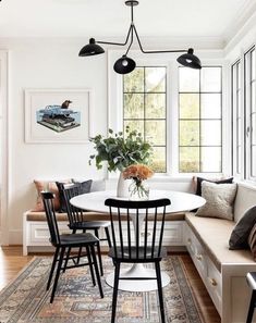 a dining room table with four chairs and a bench in front of the window,