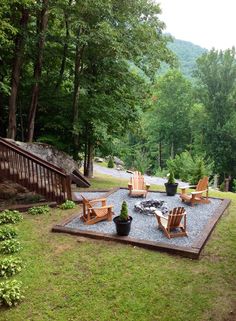 an outdoor fire pit surrounded by lawn chairs and rocks in the middle of a wooded area