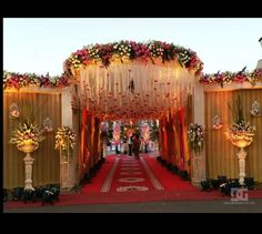 an outdoor wedding venue decorated in gold and red with flowers on the walls, pillars and columns