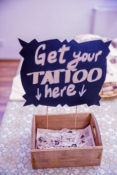 a sign that says get your tattoo here on top of a wooden box with some cookies in it