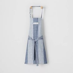 a blue and white striped apron hanging from a hook on a wall with a wooden hanger