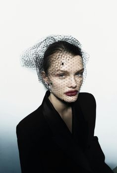 a woman wearing a veil over her head and black dress with red lipstick on it