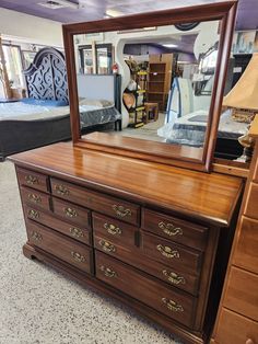 a dresser with a mirror on top of it in a room filled with furniture and other items