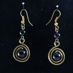 the earrings are made with gold and black glass bead, wire wrapped around them