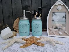 two blue mason jars sitting on top of a table next to shells and starfish