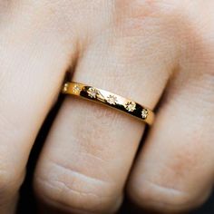 a close up of a person's hand with a gold ring on their finger