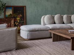 a living room filled with furniture and a painting on the wall next to a coffee table