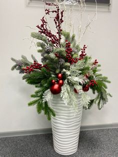 a white vase filled with christmas decorations and greenery