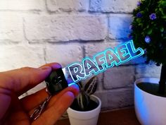 a person is holding up the word raffel in front of a potted plant