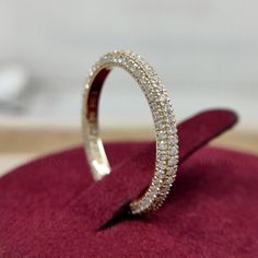 a diamond wedding band sitting on top of a red velvet cushion in a display case