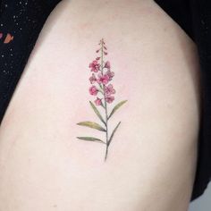 a small pink flower tattoo on the back of a woman's left thigh,