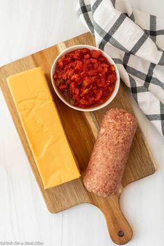 a wooden cutting board topped with meat and cheese next to a bowl of tomato sauce