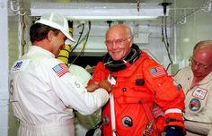 two men in orange spacesuits standing next to each other and one man wearing an oxygen suit