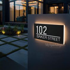 an illuminated sign on the side of a building that reads 103 baker street at night