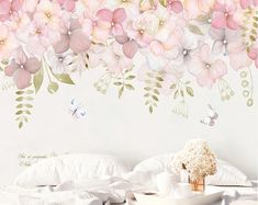 a white bed sitting under a pink flower covered wall