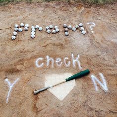 a baseball field with the words check written in white chalk and a green bat laying on it