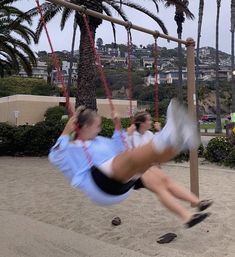 a woman swinging on a rope with palm trees in the background