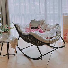 a woman laying in a chair with a book on her lap and looking at the screen