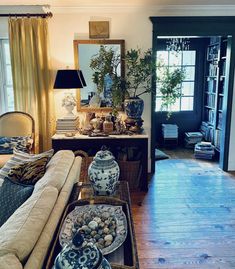 a living room filled with lots of furniture and decor on top of a hard wood floor