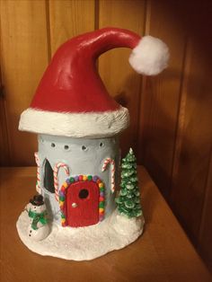 a santa hat on top of a house with trees and candy canes around it